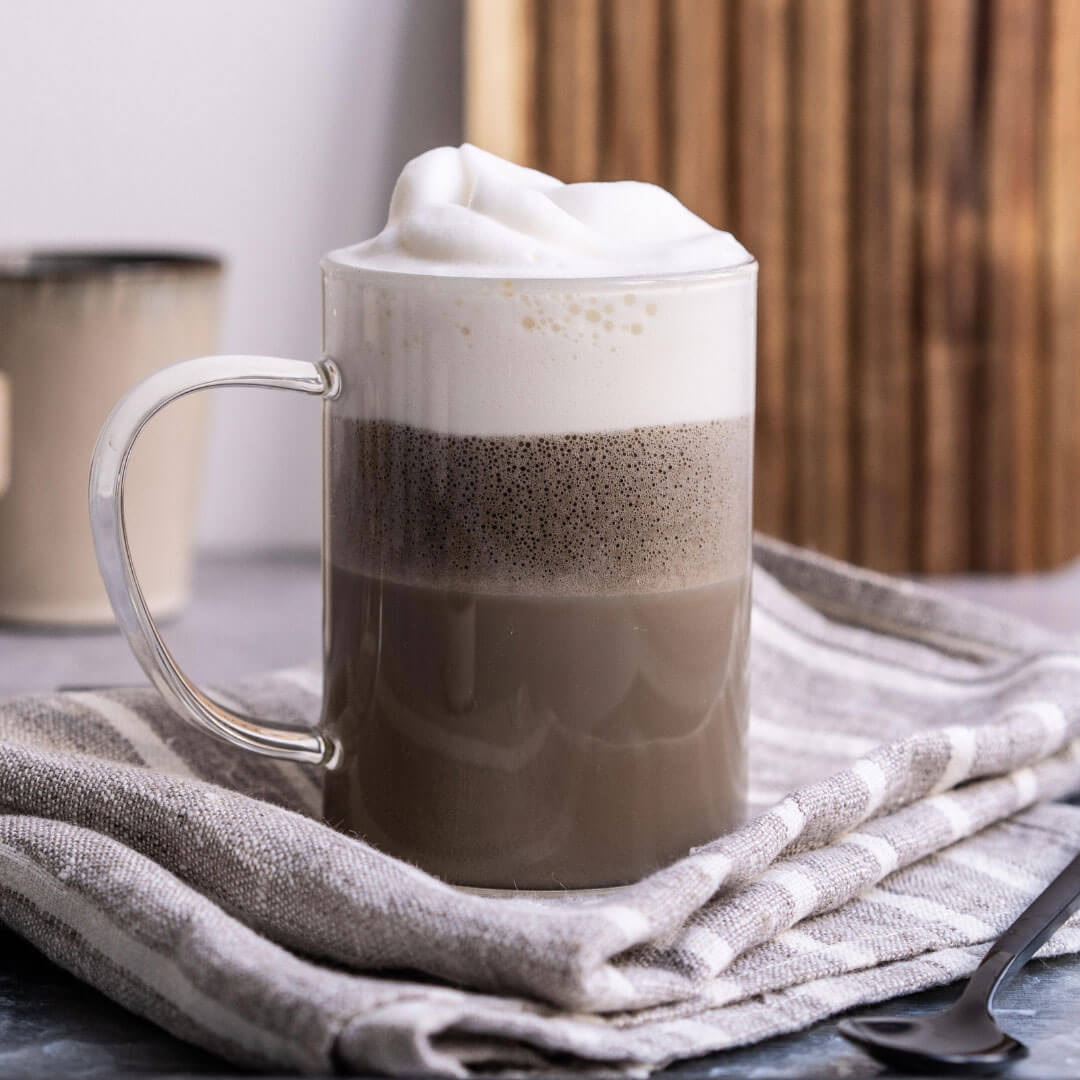 Mug of hojicha with whipped cream on a textured surface