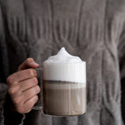 Hand holding a mug of hojicha with a blurred background