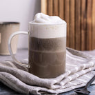 Mug of hojicha with whipped cream on a textured surface