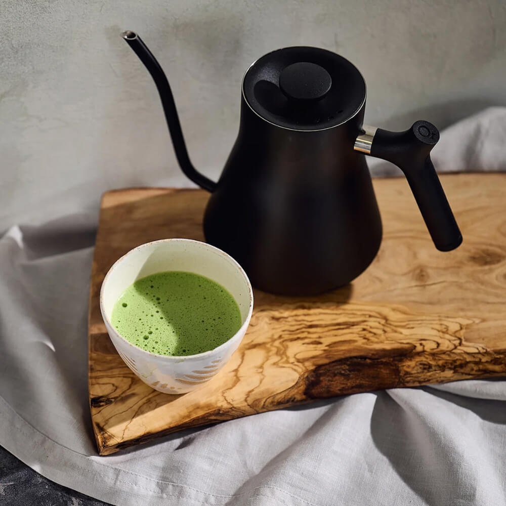 Matcha tea in cup with black teapot