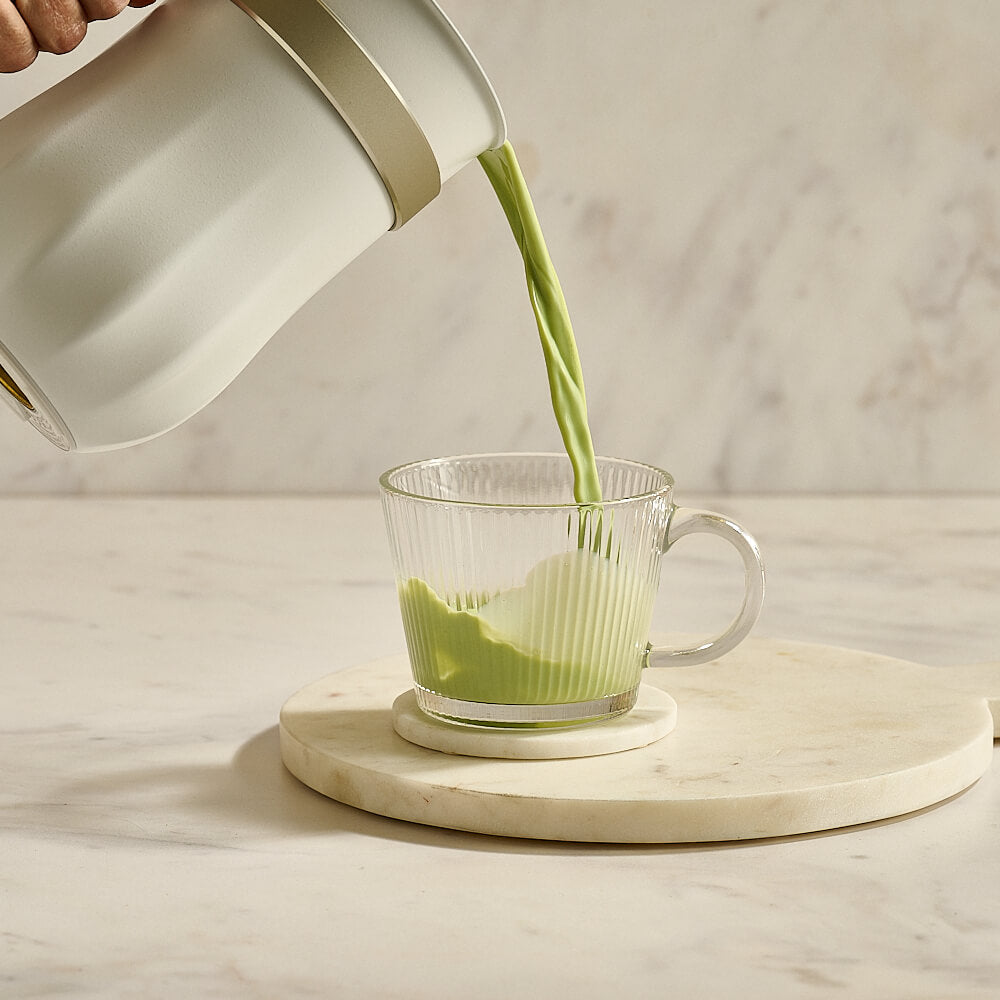 Matcha tea being poured into glass mug