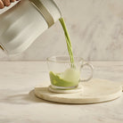Matcha tea being poured into glass mug