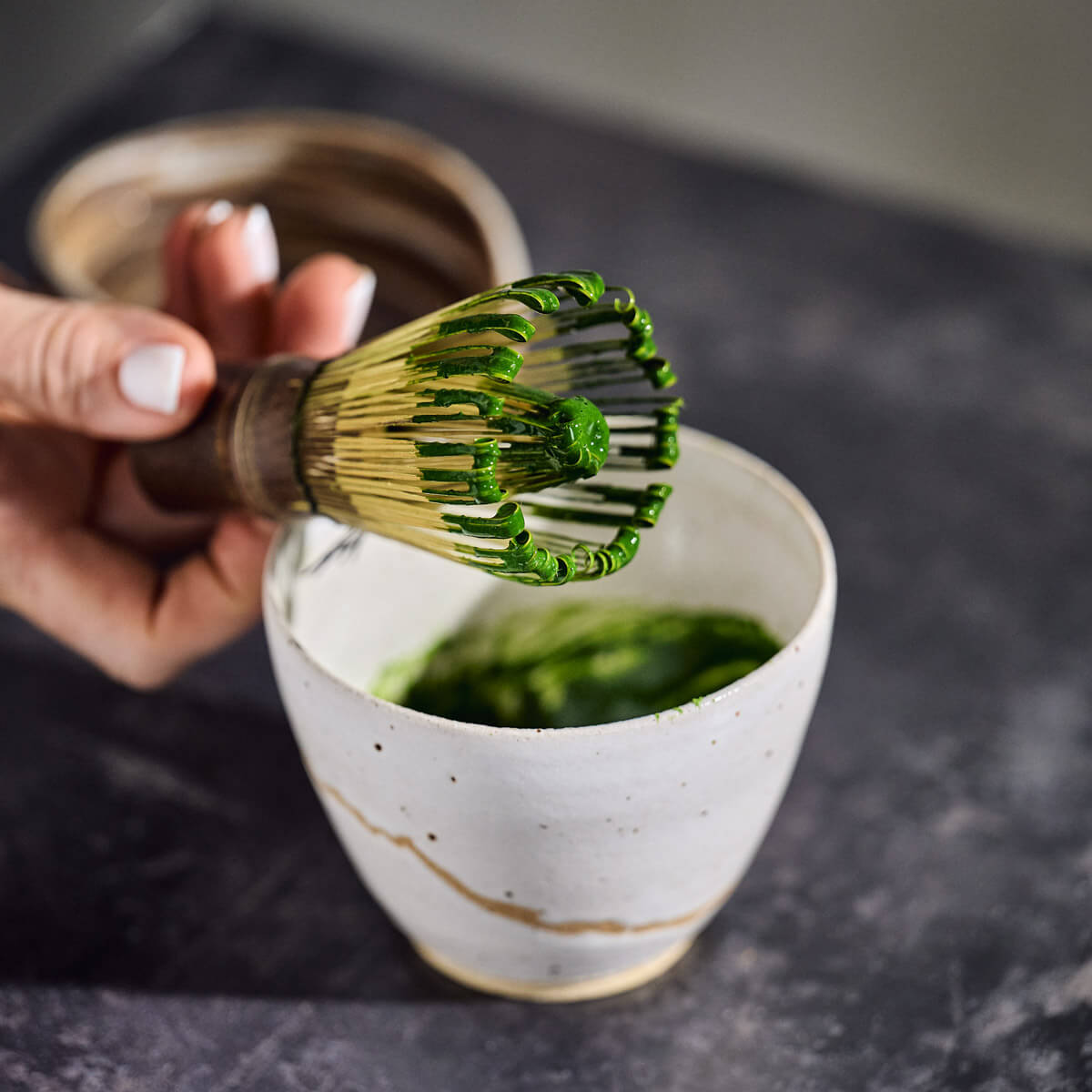 matcha tea being prepared with match whisk